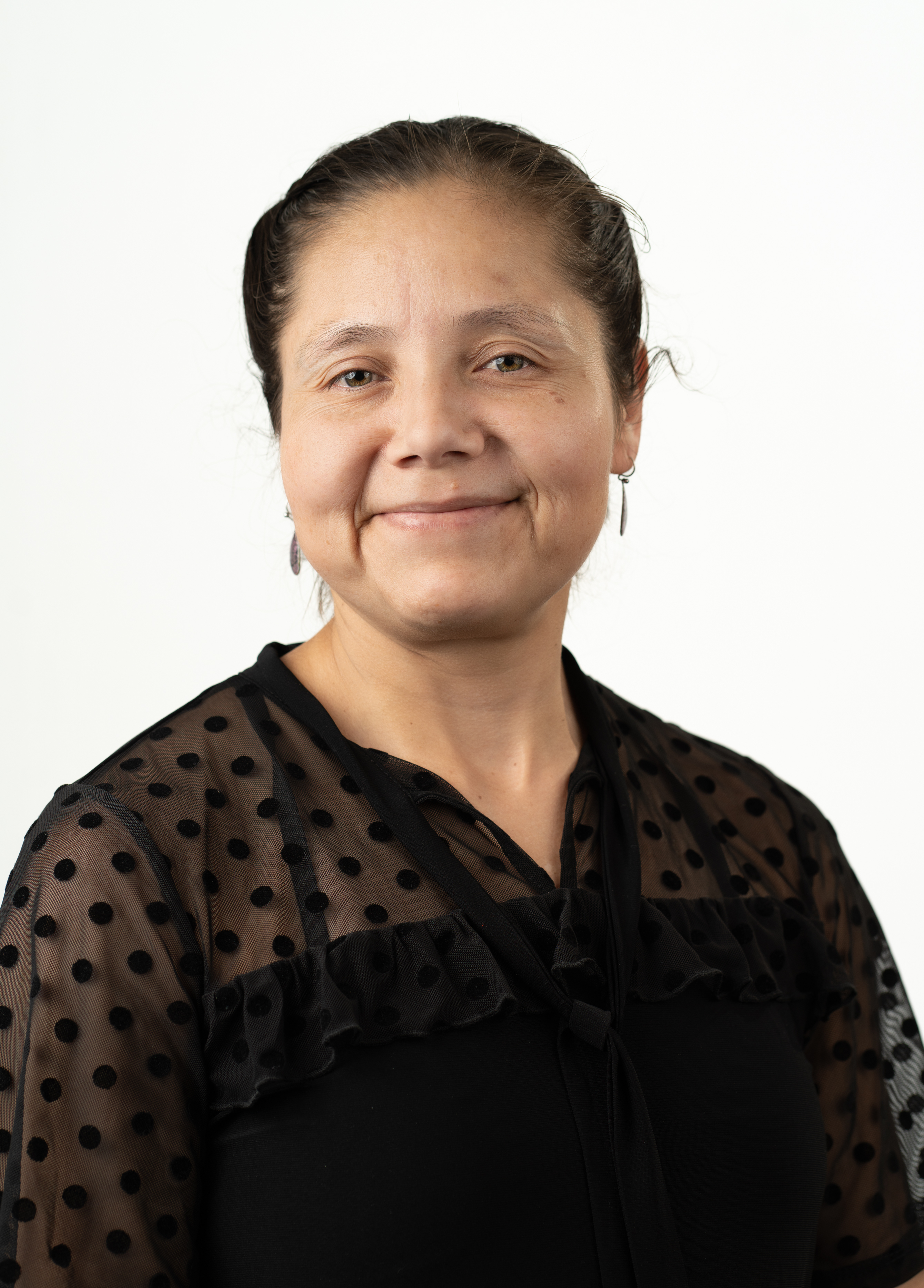 Dr. Karla Robles Lopez dressed in a black shirt stands in front of a white background smiling slightly