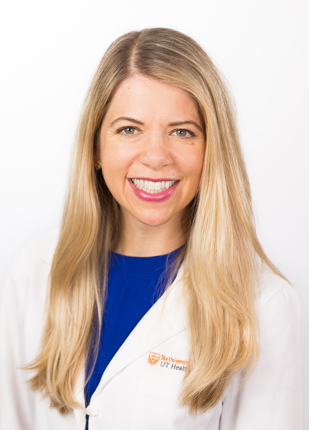 Katherine Boos wearing a white coat and smiling in front of a white backdrop.