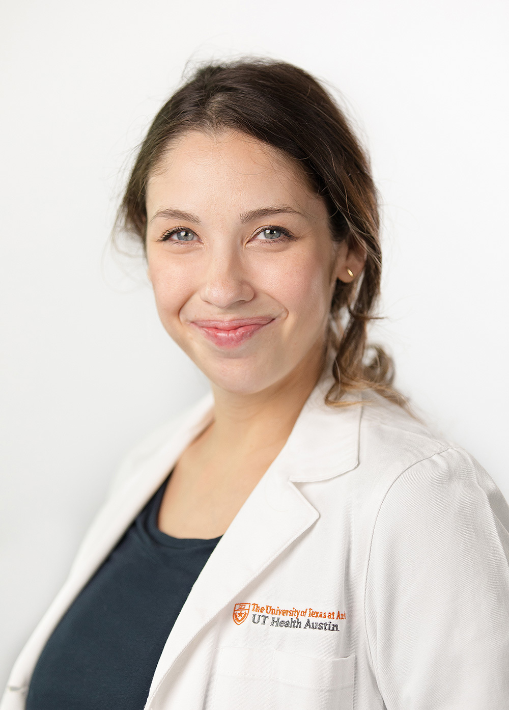 Kayleigh Todd wearing a white coat and smiling in front of a white backdrop.