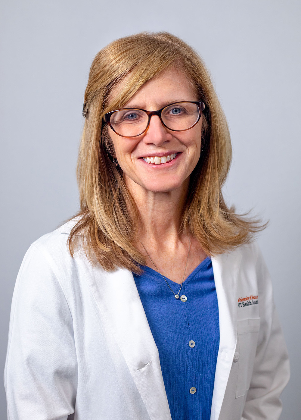 Kelly Gettig wearing a white coat and smiling in front of a white backdrop.