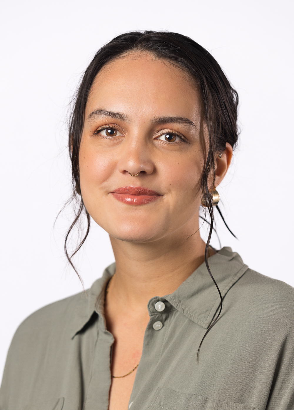 Social worker Kelsie Piedra, LCSW, smiling in front of a white backdrop. She is wearing an olive drab gray blouse.