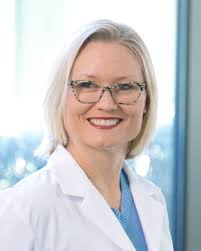 Dr. Kirsten Nieto wearing a white coat and smiling in front of a window.