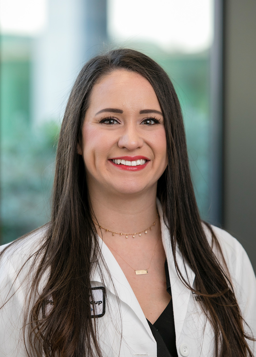 Lauren Pokala wearing a white coat and smiling indoors.