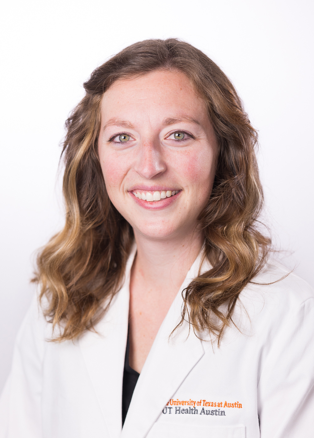 Lauren Westin wearing a white coat and smiling in front of a white backdrop.