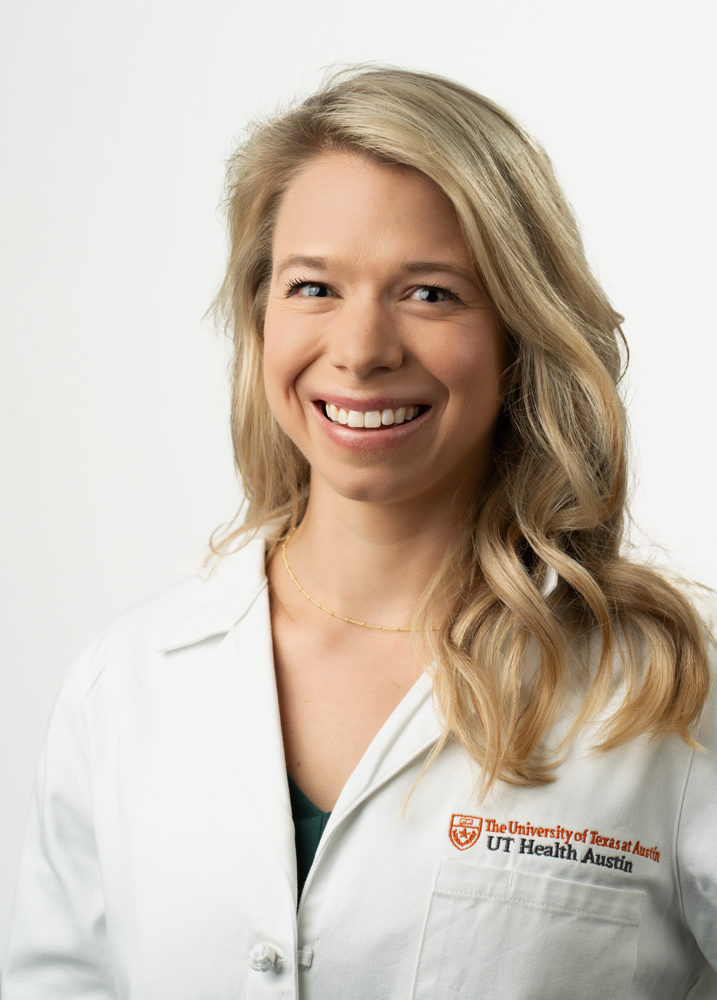 Advanced nurse practitioner Maggie Goss stands in front of a white background smiling