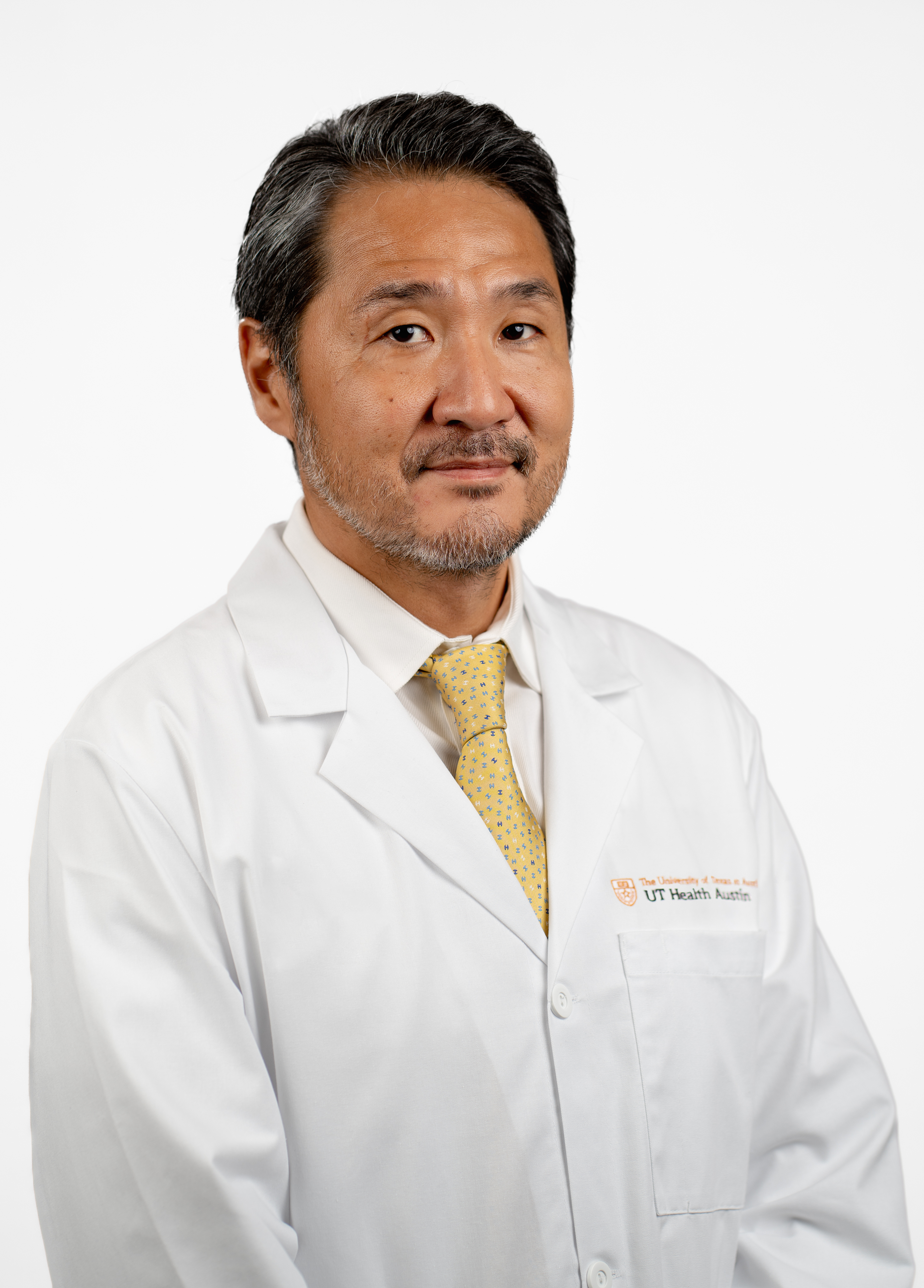 Heart surgeon Ono Masahiro, MD stands in front of a white backdrop with a serious, professional gaze on his face.