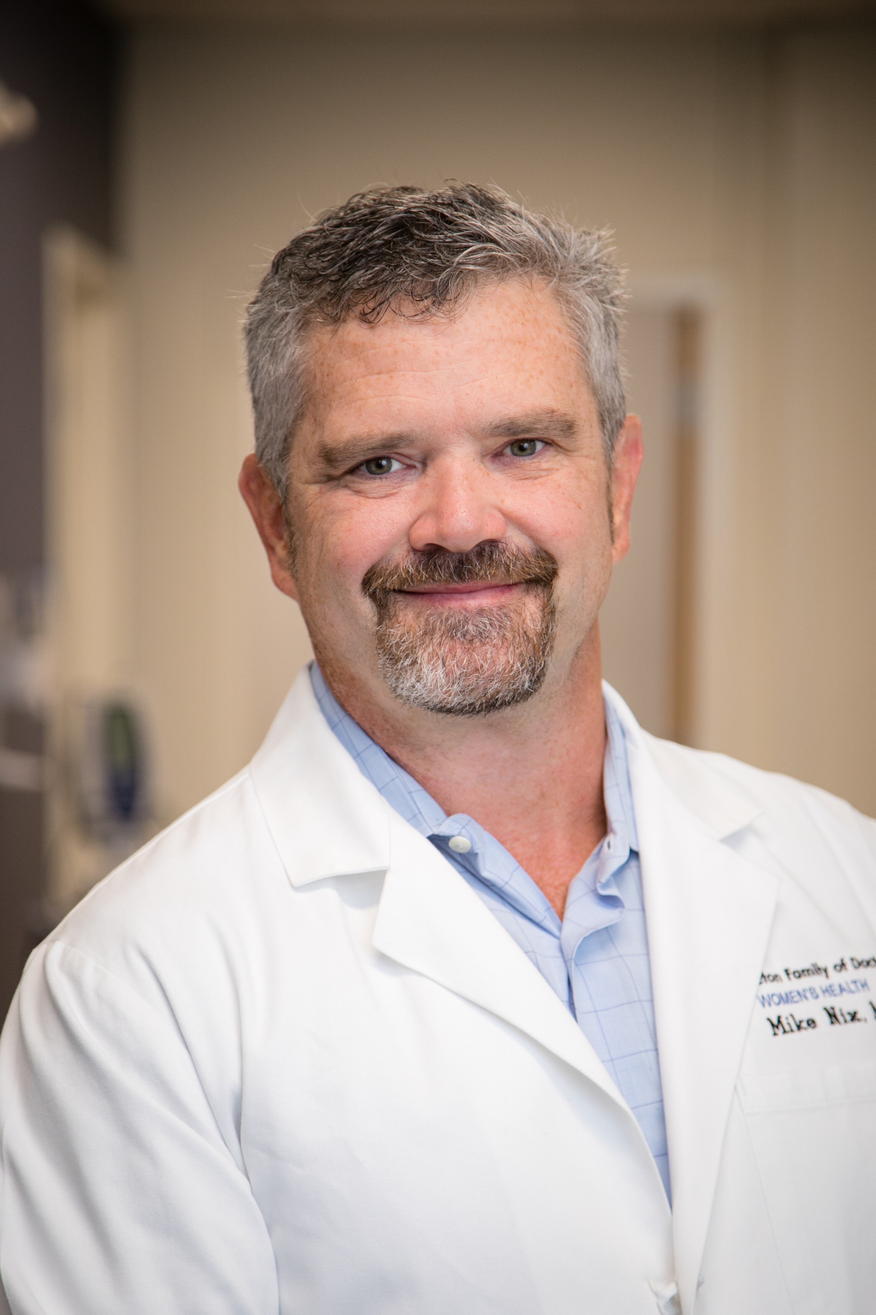 Dr. Michael Nix wearing a white coat and smiling indoors.