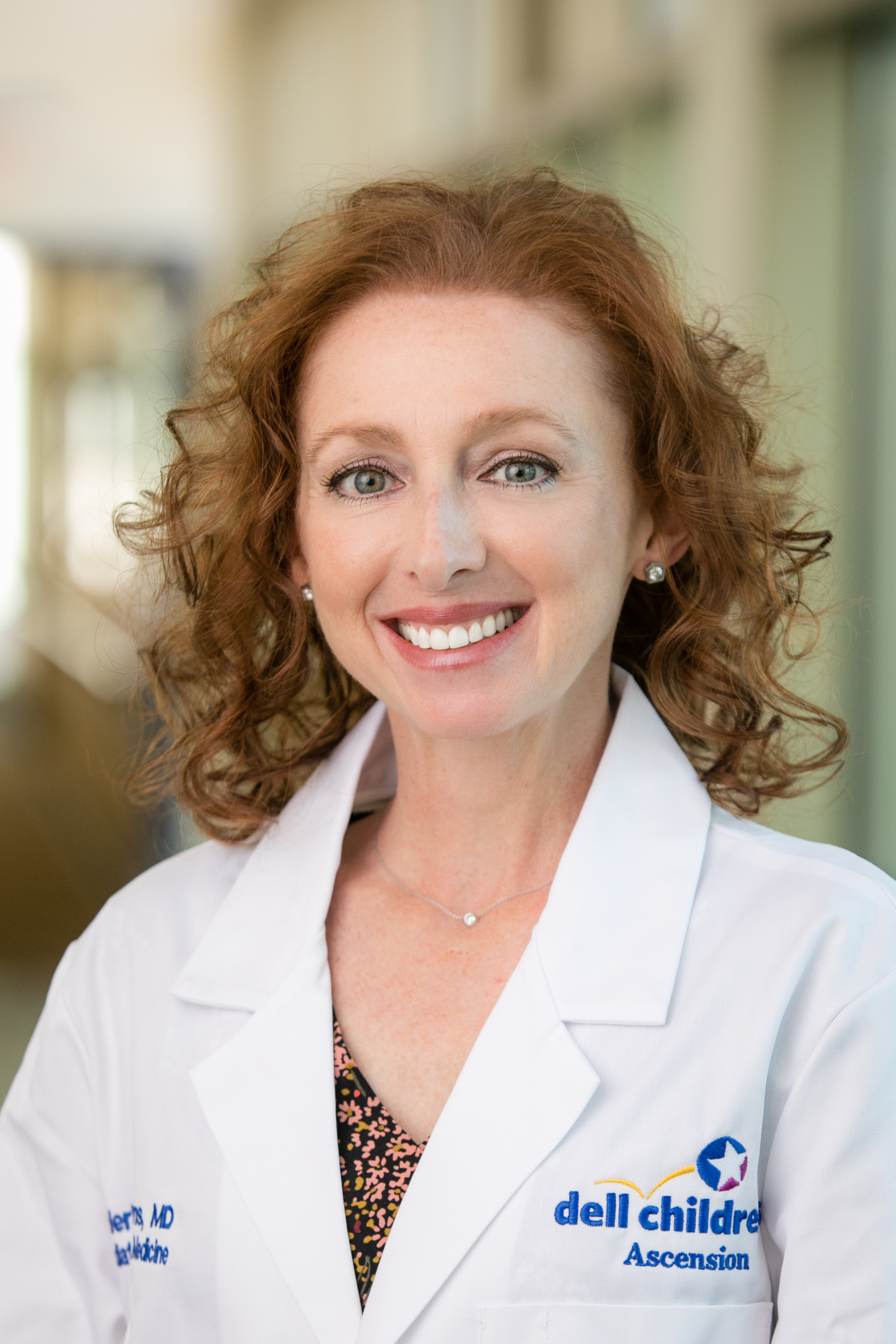 Dr. Natalie Frost wearing a white coat and smiling indoors.