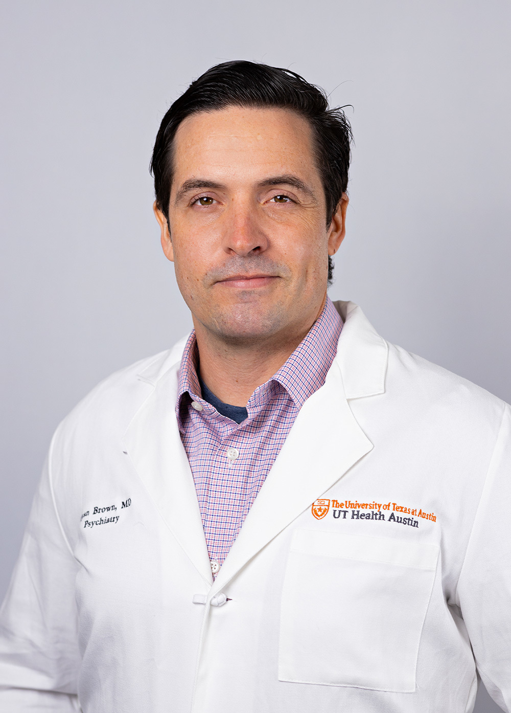 Dr. Ryan Brown wearing a white coat and smiling in front of a white backdrop.