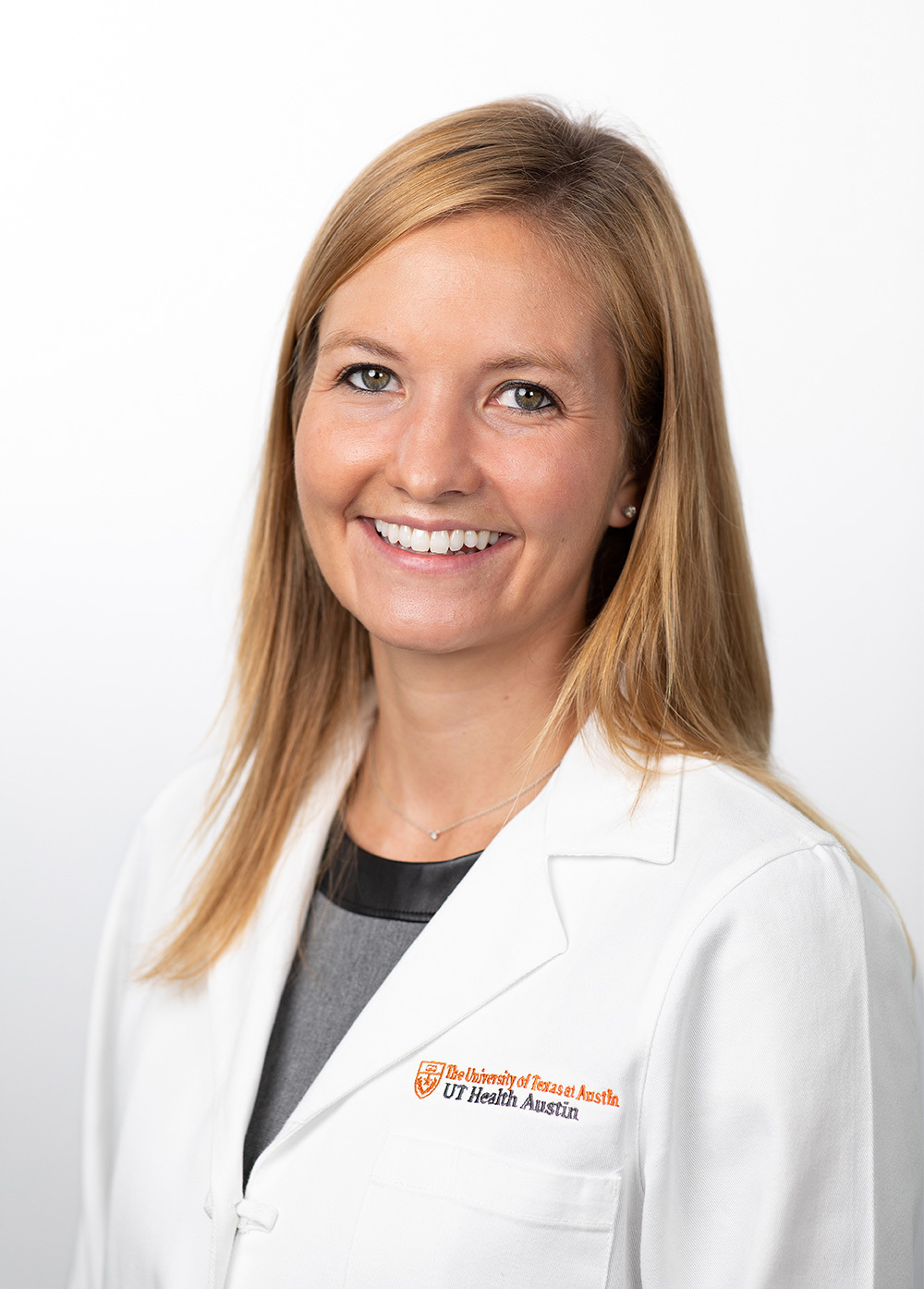 Dr. Sara Pavitt wearing a white coat and smiling in front of a white backdrop.