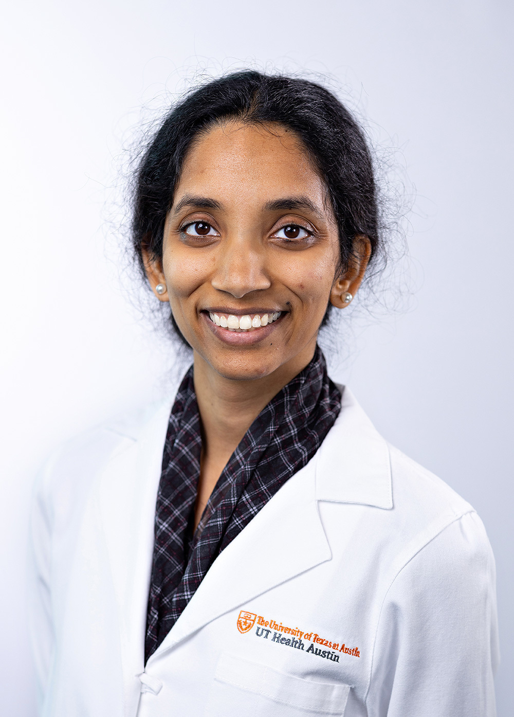 Dr. Vandana Vedanarayanan wearing a white coat and smiling in front of a white backdrop.