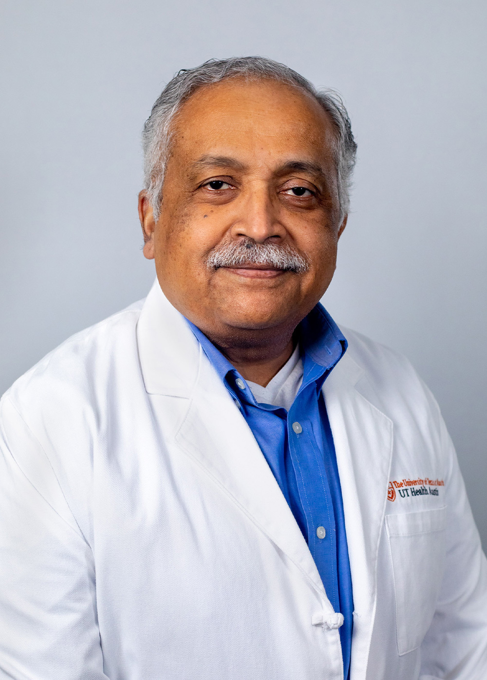 Dr. Vettaikorumakankav Vedanarayanan wearing a white coat and smiling in front of a white backdrop.