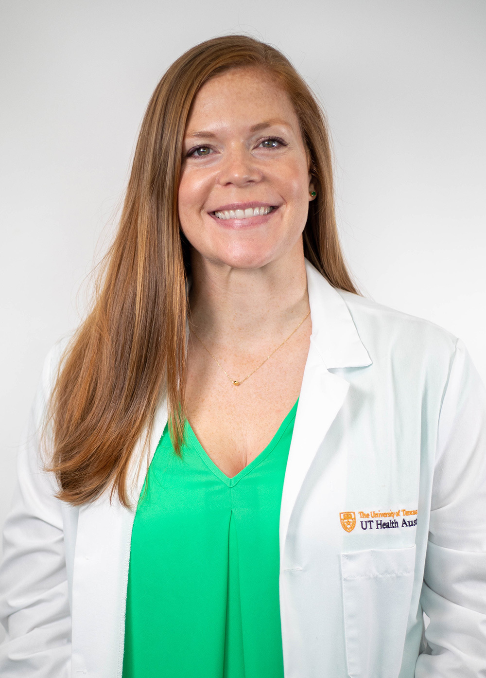 Jamie Shanahan wearing a white coat and smiling in front of a white backdrop.
