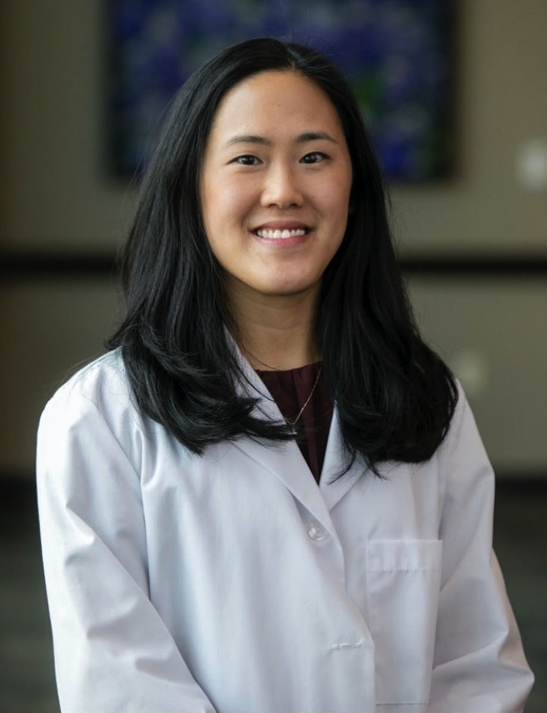Dr. Jennifer Hughes wearing a white coat and smiling indoors.