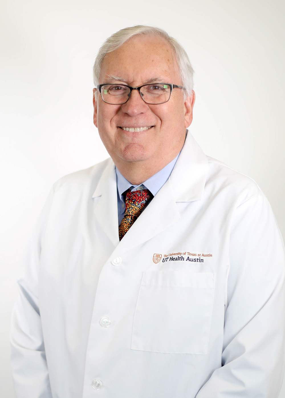 Dr. Steve Roach wearing a white coat and smiling in front of a white backdrop.