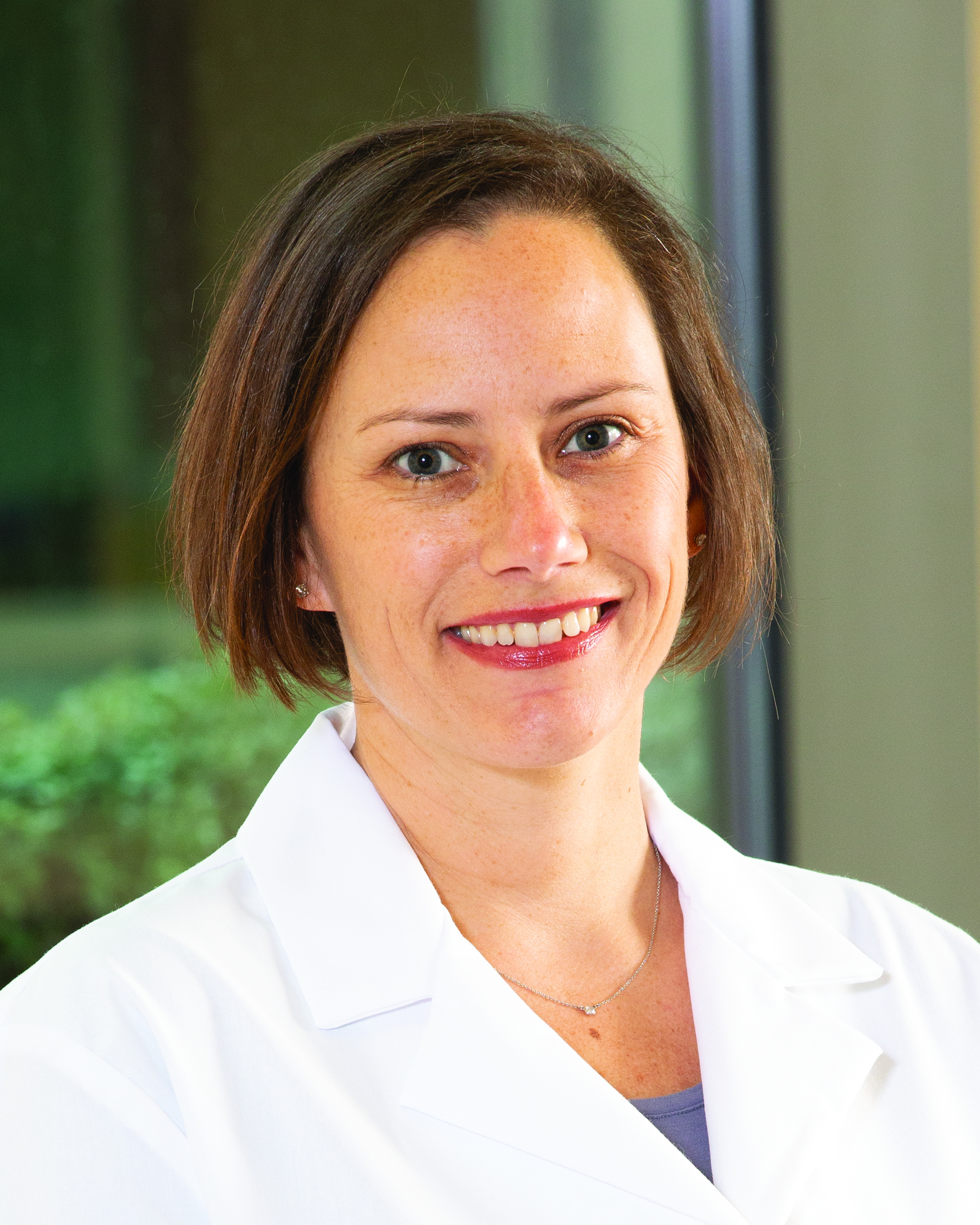 Pediatric hospitalist Toni Wakefield, MD, FAAP, wearing a white coat and smiling near a window.