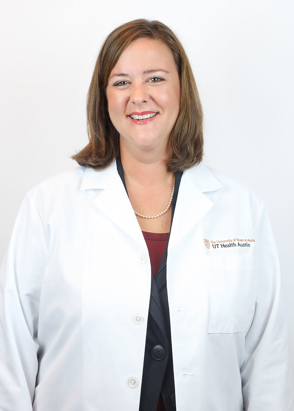 Dr. Amanda White wearing a white coat and smiling in front of a white backdrop.