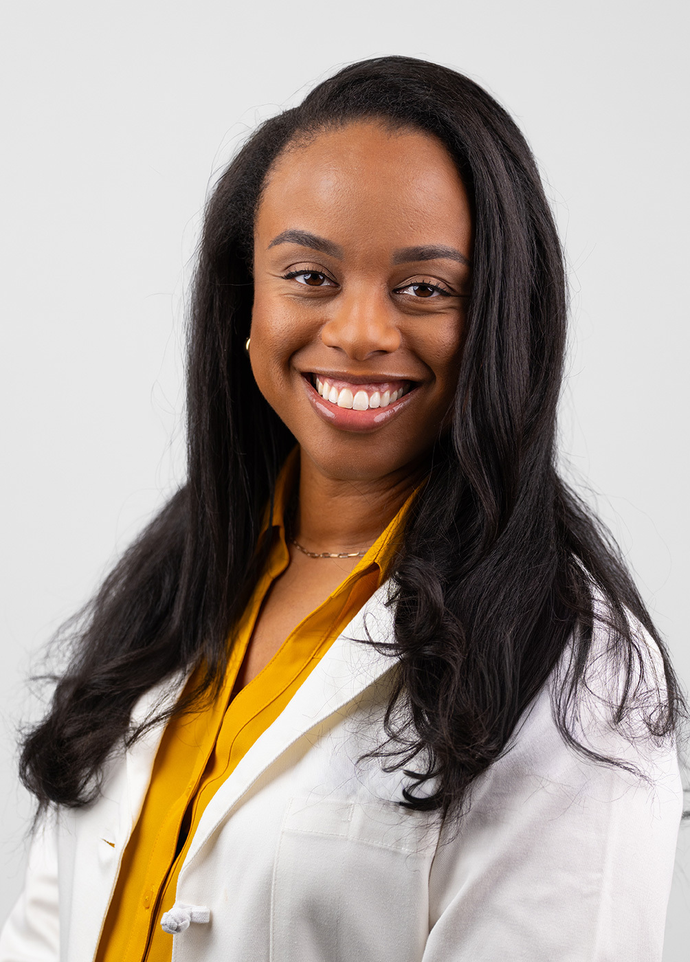 Headshot of Ashley Griffin. She is wearing a yellow blouse and a white coat.