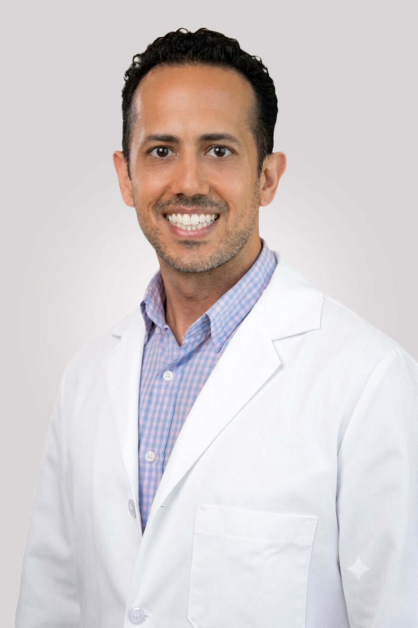 A headshot of Hirsh Trivedi. He is wearing a blue and pink checkered dress shirt and a white coat.